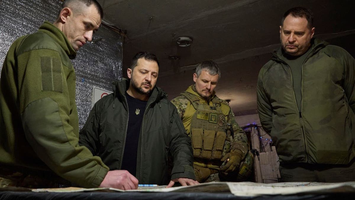 Ukrainian President Volodymyr Zelenskyy looking at battleground plans with military leaders