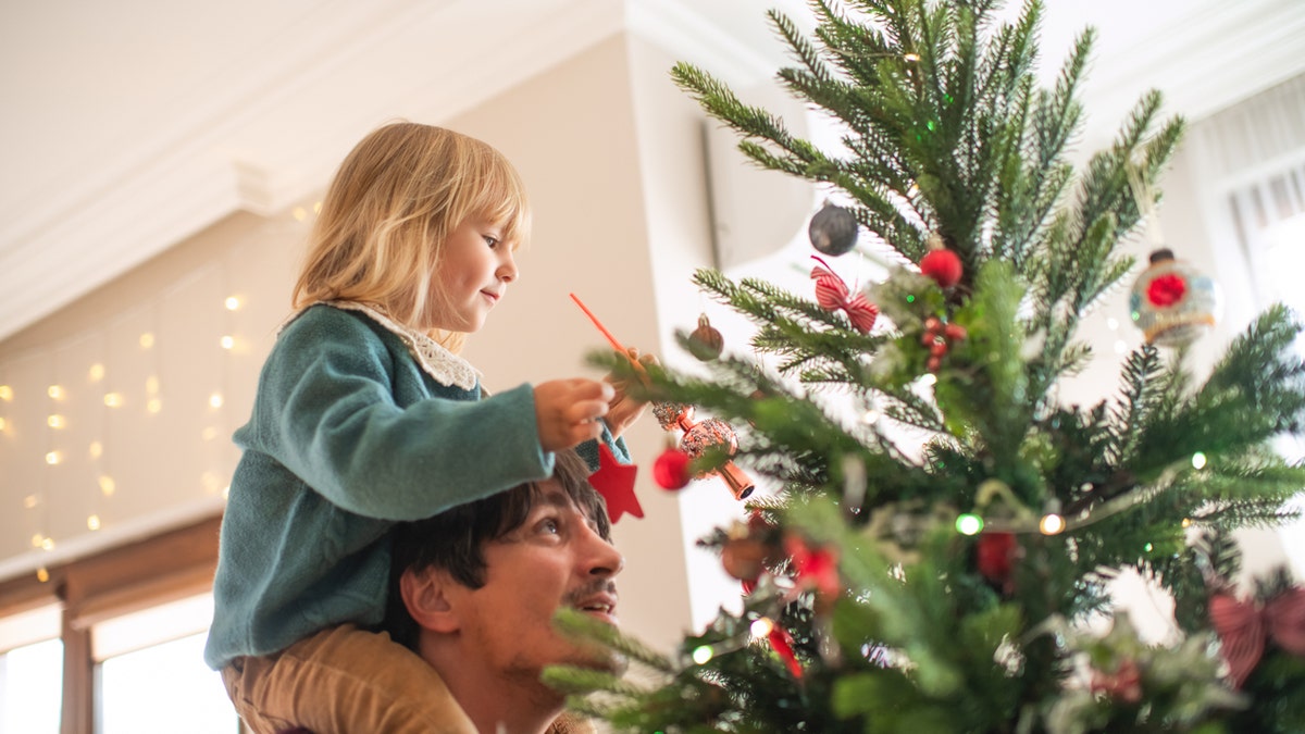 Father and daughter decorating Christmas tree