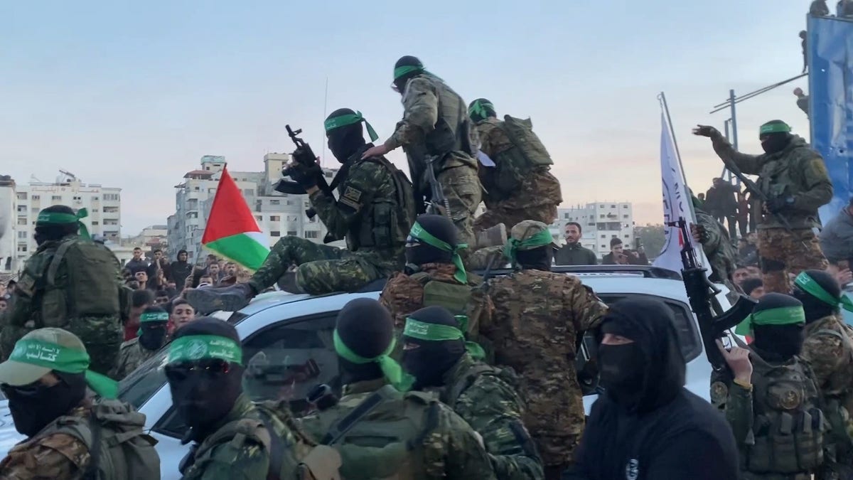 Hamas terrorists emerging from the shadows as they surround Red Cross vehicles.  