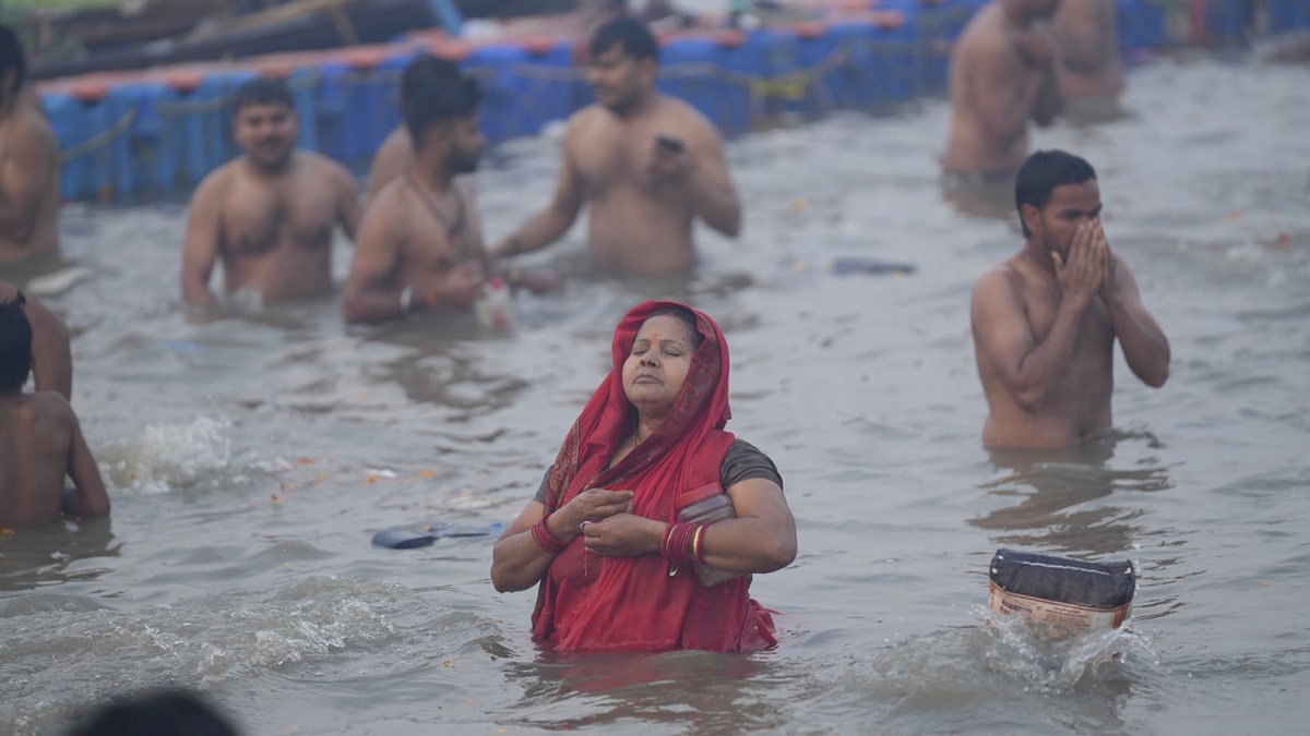 A Hindu woman dressed in red takes a holy dip in sacred waters.