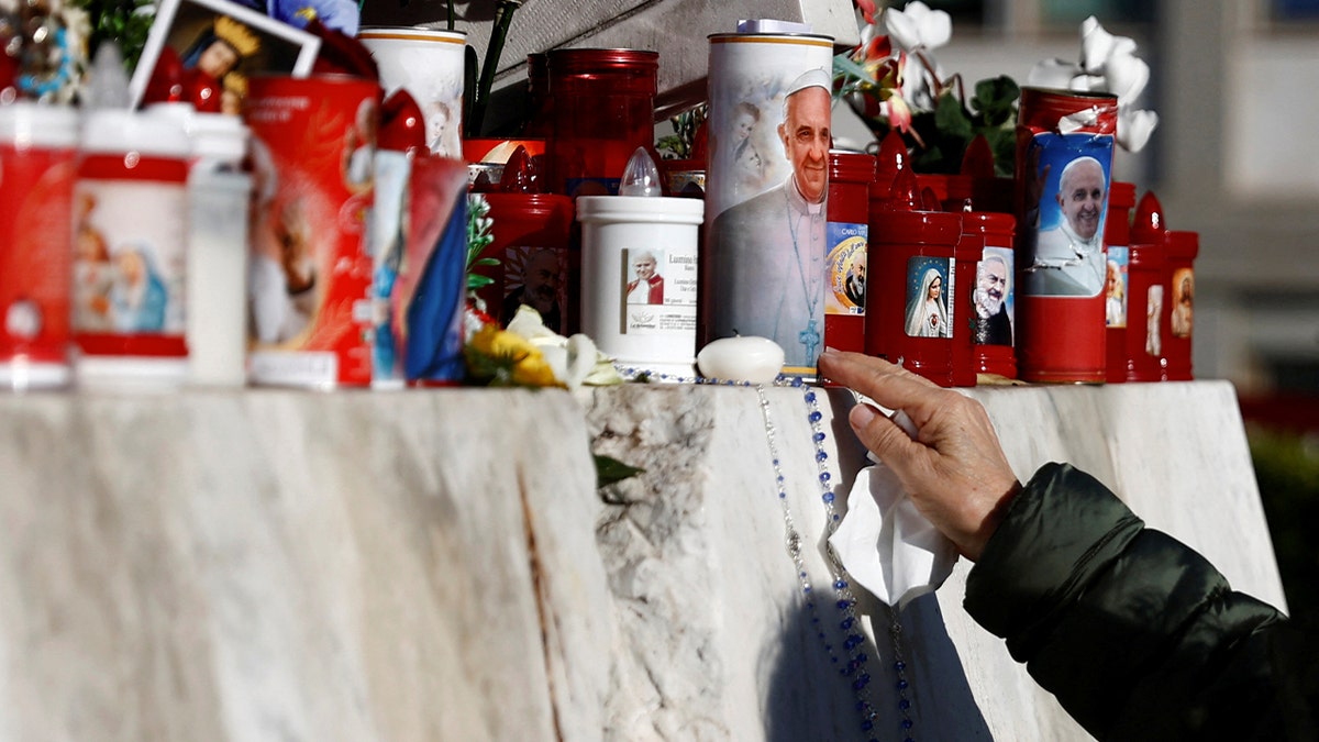 Person prays outside of hospital where Pope Francis is being treated