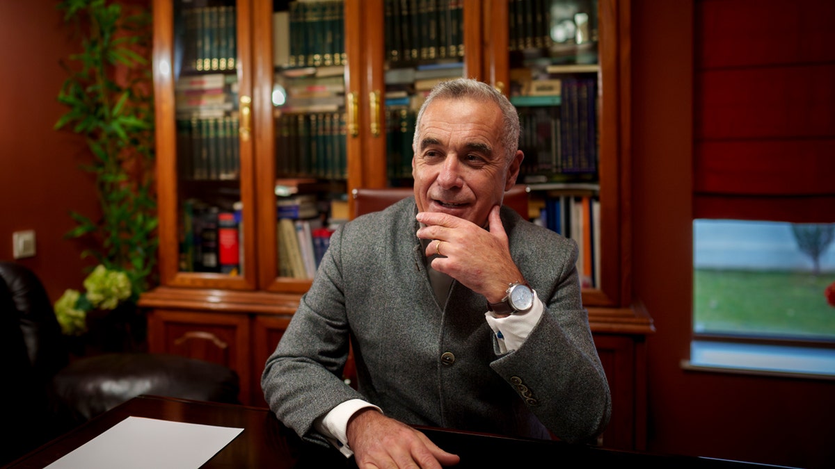 Romanian presidential candidate Calin Georgescu sits at a desk.