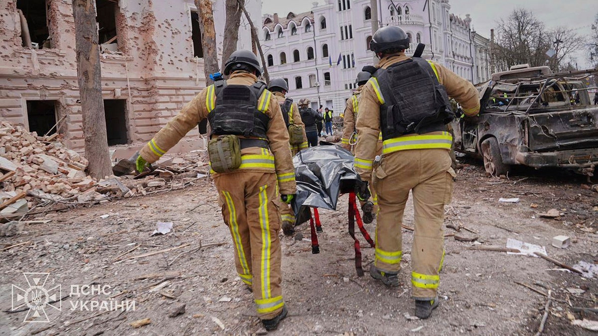 firefighters carry a body of a victim