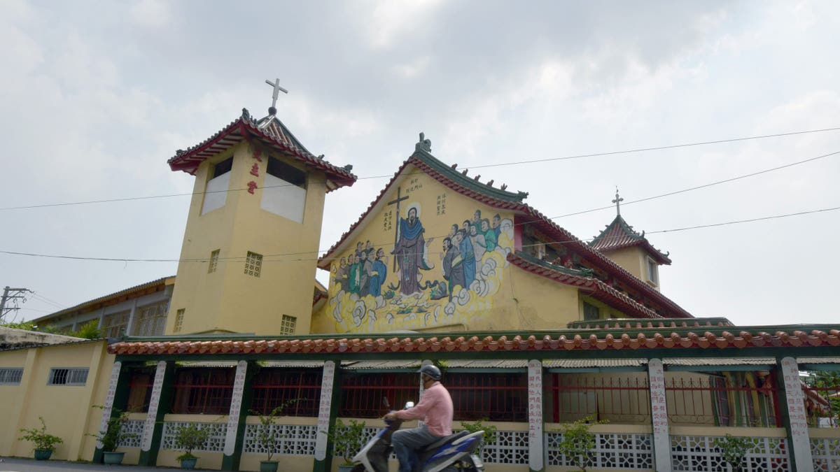 Motorcyclist riding past the Holy Spirit Church in Yanshui