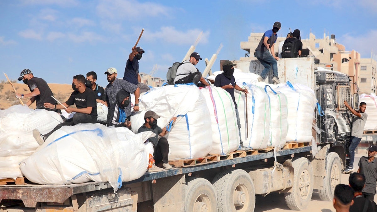 Hamas terrorists carrying clubs and firearms secure humanitarian aid trucks in the northern Gaza area of Jabaliya on June. 25.