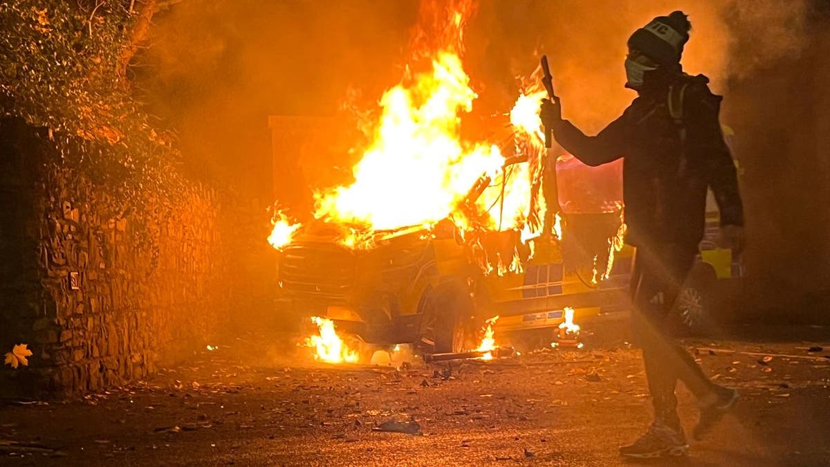 Protester films as Garda vehicle burns during violent Dublin protest.
