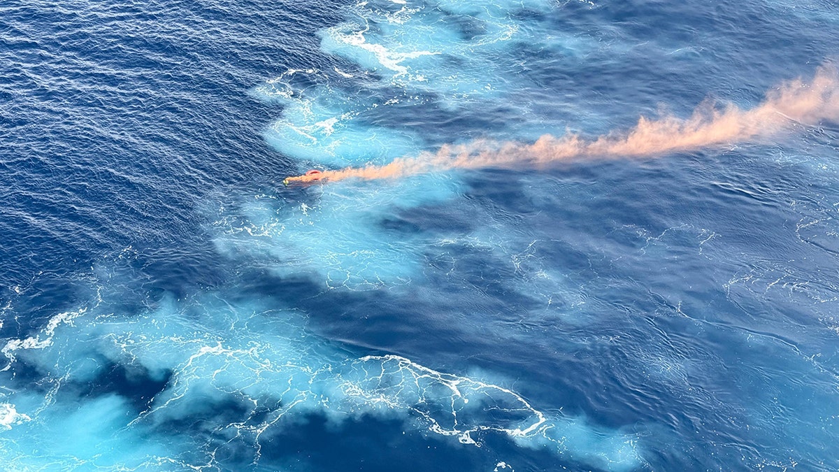 flare billowing orange smoke as it floats in the blue sea