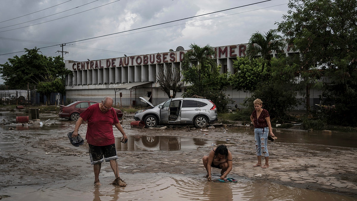 People walking along road covered in murky water