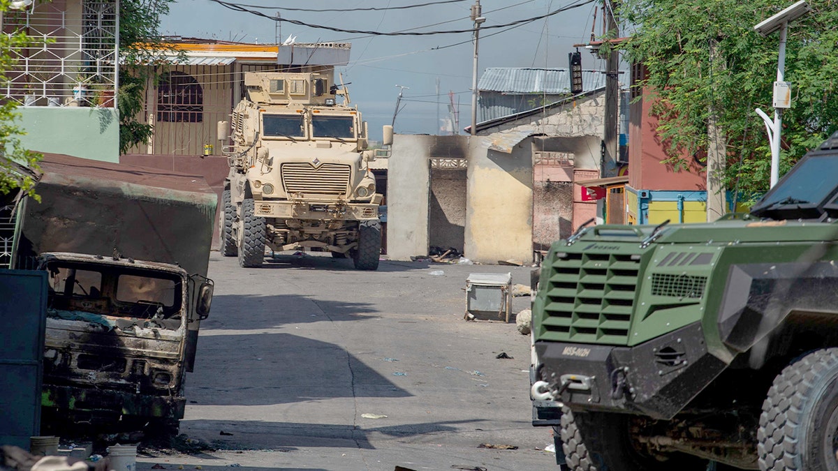 An armored police vehicle moves through a tense urban neighborhood in Port-au-Prince.