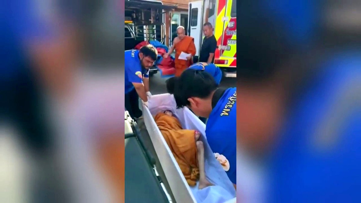 emergency personnel begin to transport woman in coffin to hospital