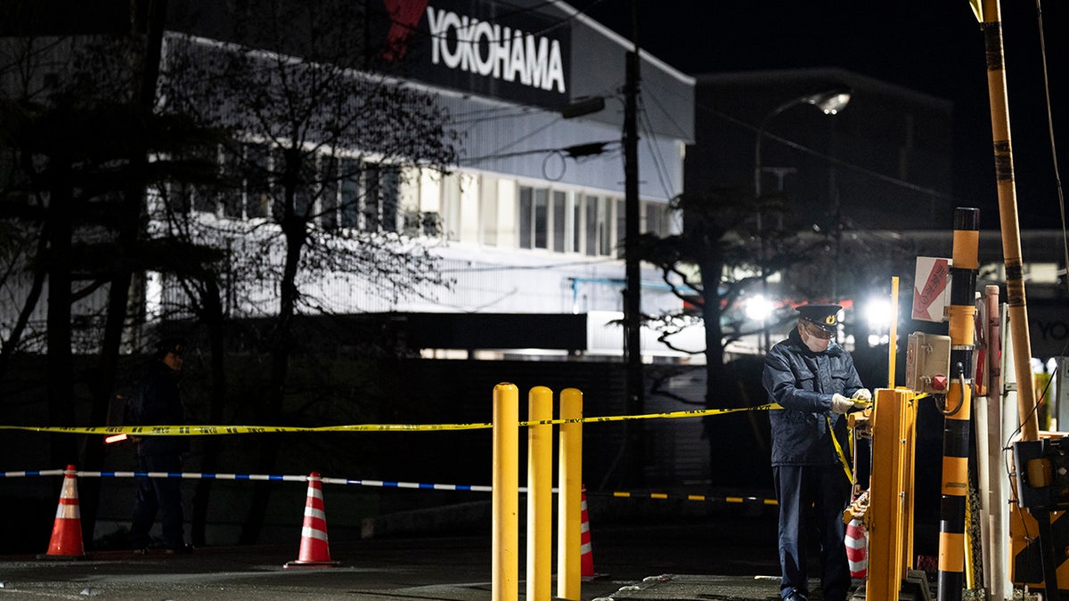 Police officer stands outside Yokohama factory in Japan following attack there