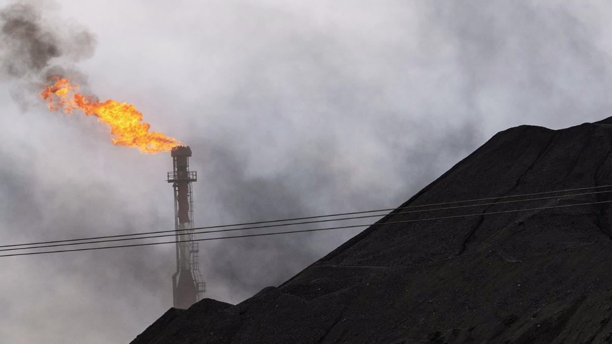 A gas flare behind a coal pile in Venezuela on May 22, 2023.
