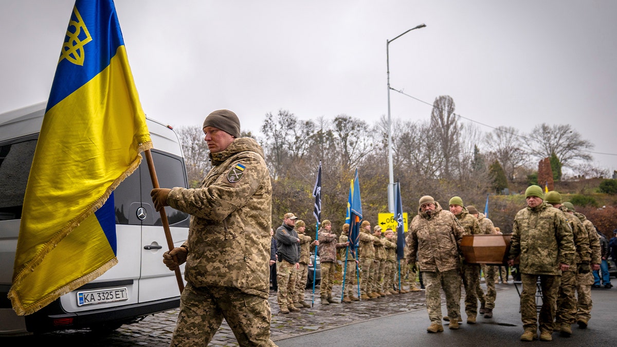 Pallbearers in military uniform carry a flag-draped coffin during a solemn funeral ceremony in Kyiv.