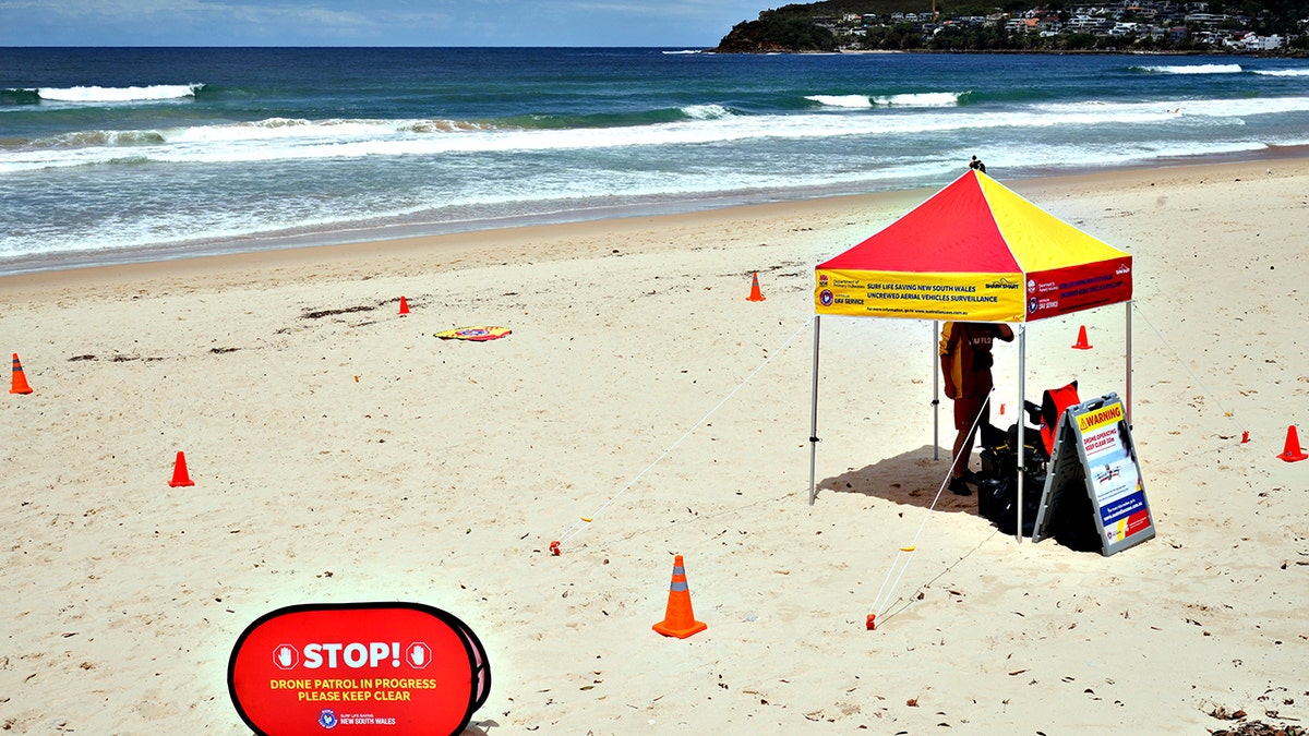 man on beach using drone to scan ocean waters