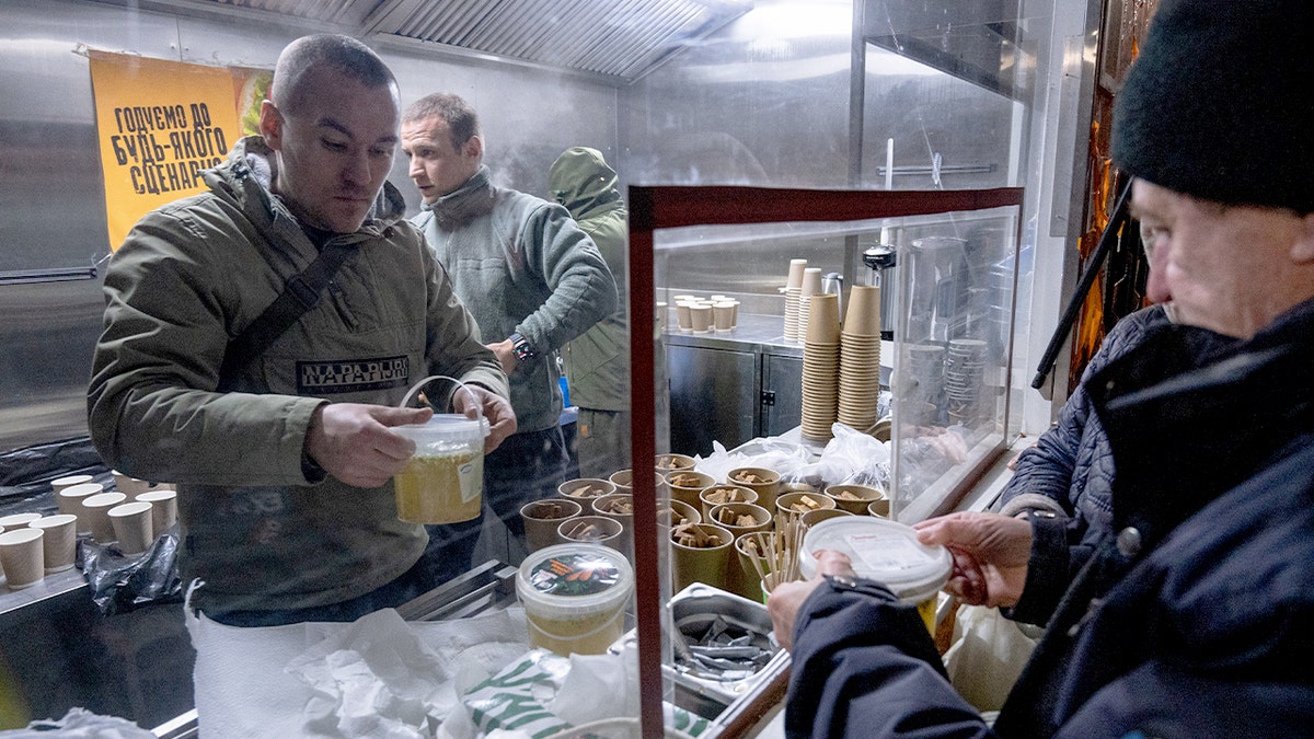 Military veterans distribute hot food to residents in a neighborhood affected by power outages.