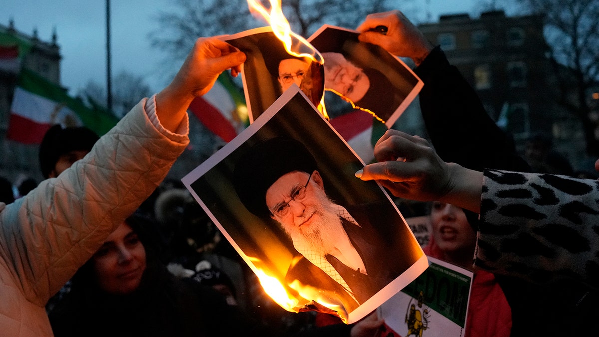 Protestors burn images of Ayatollah Ali Khamenei.