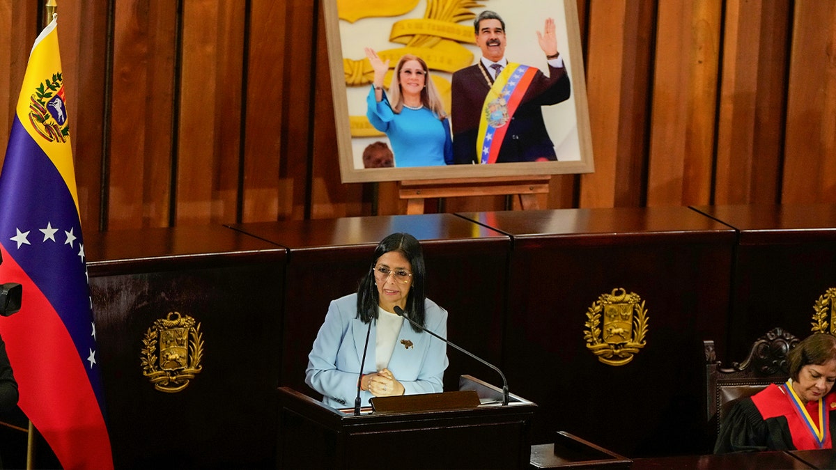 Delcy Rodriguez stands in front of a portrait of Nicolás Maduro and his wife
