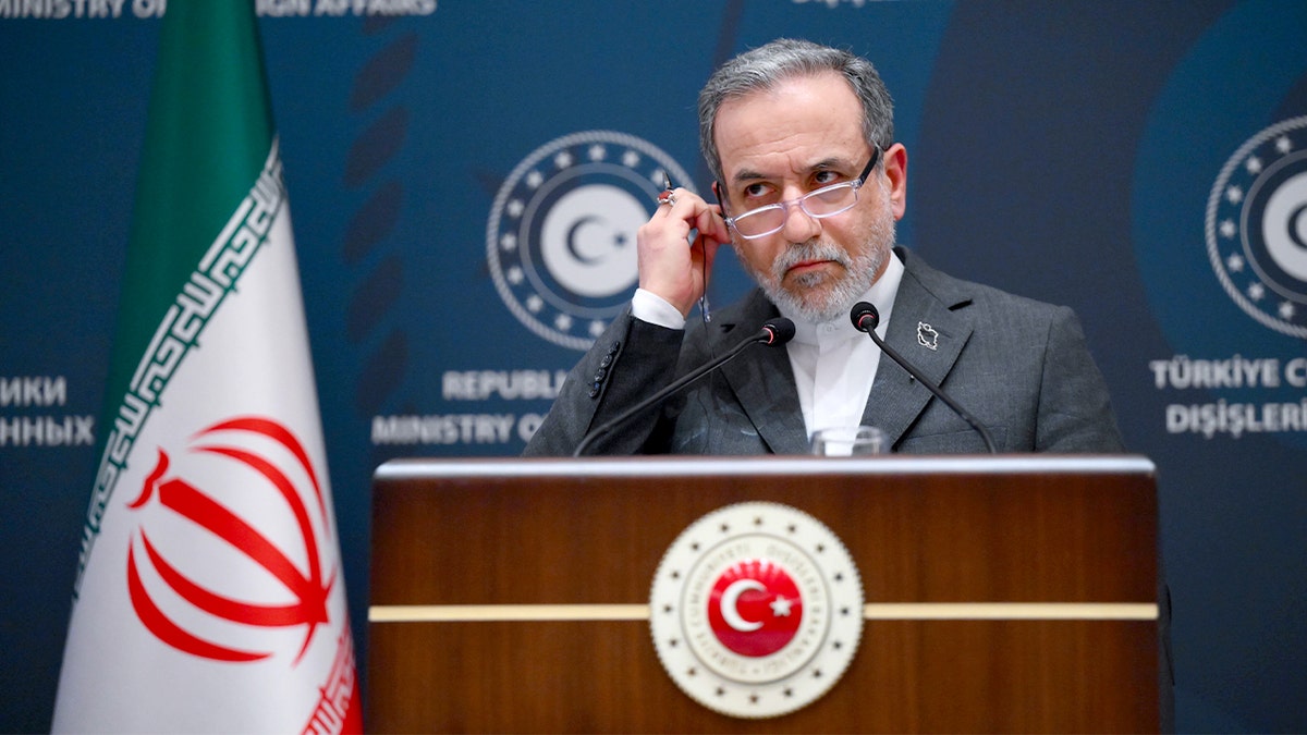 Iranian foreign minister speaks at a podium during a diplomatic press conference.