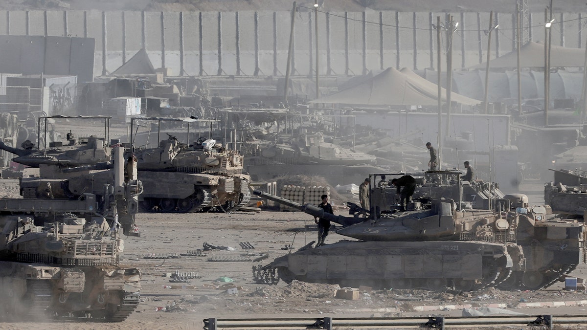 Israeli soldiers stand on military vehicles