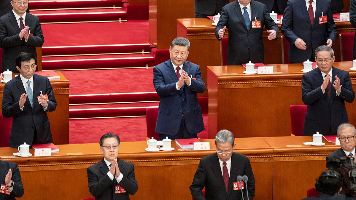 Chinese President Xi Jinping stands with senior leaders as they applaud during a legislative session inside Beijing’s Great Hall of the People.