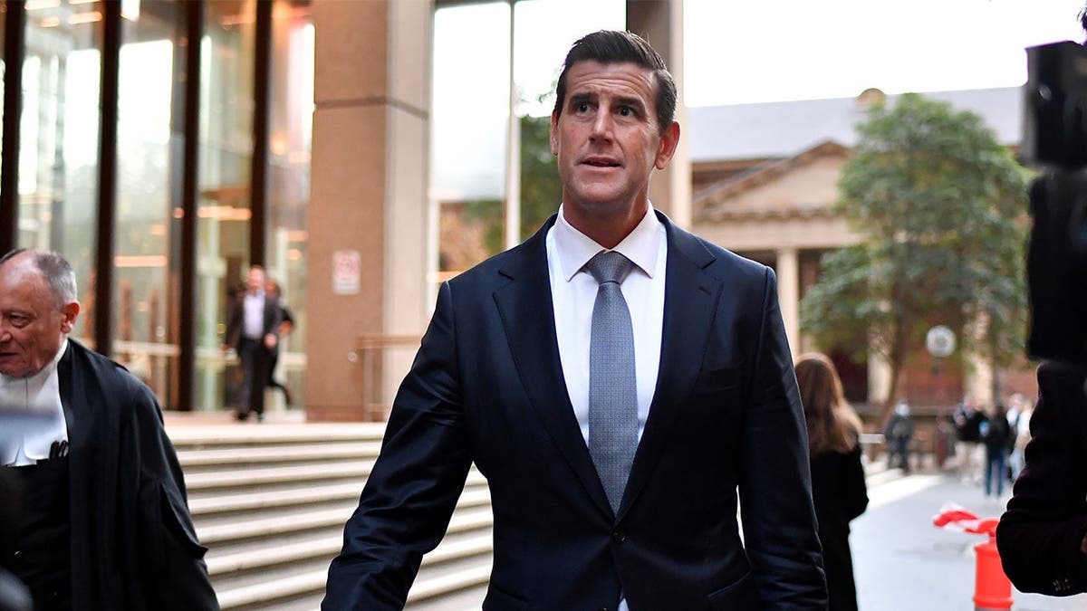 Ben Roberts-Smith walking away from the Federal Court of Australia while wearing a dark suit and blue tie.