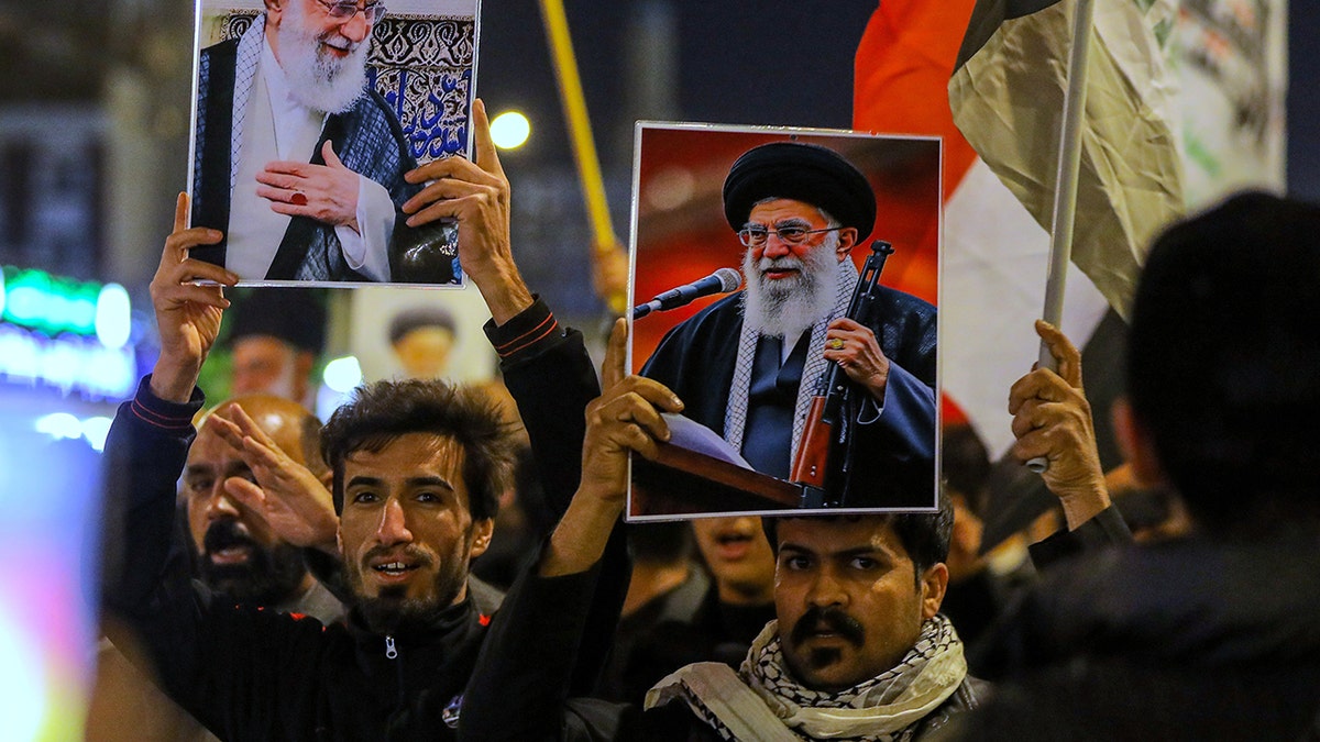 Iraqi Shiite men holding pictures of Ayatollah Ali Khamenei during a gathering in Najaf