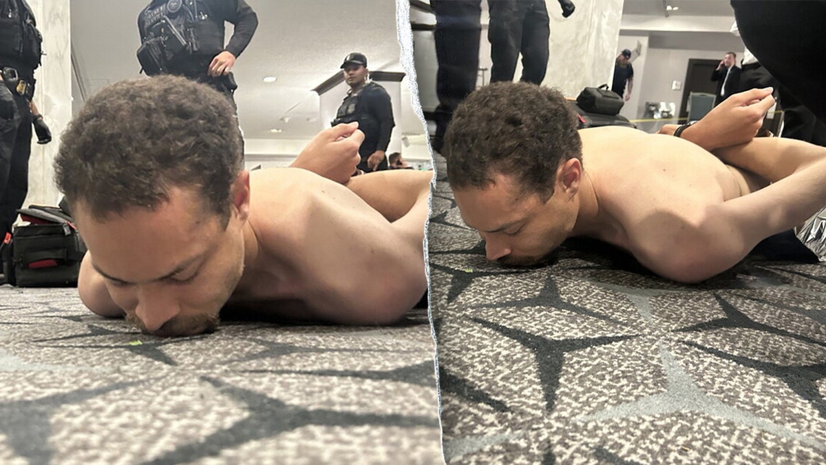 A suspect lying face down on the floor as law enforcement officers detain him