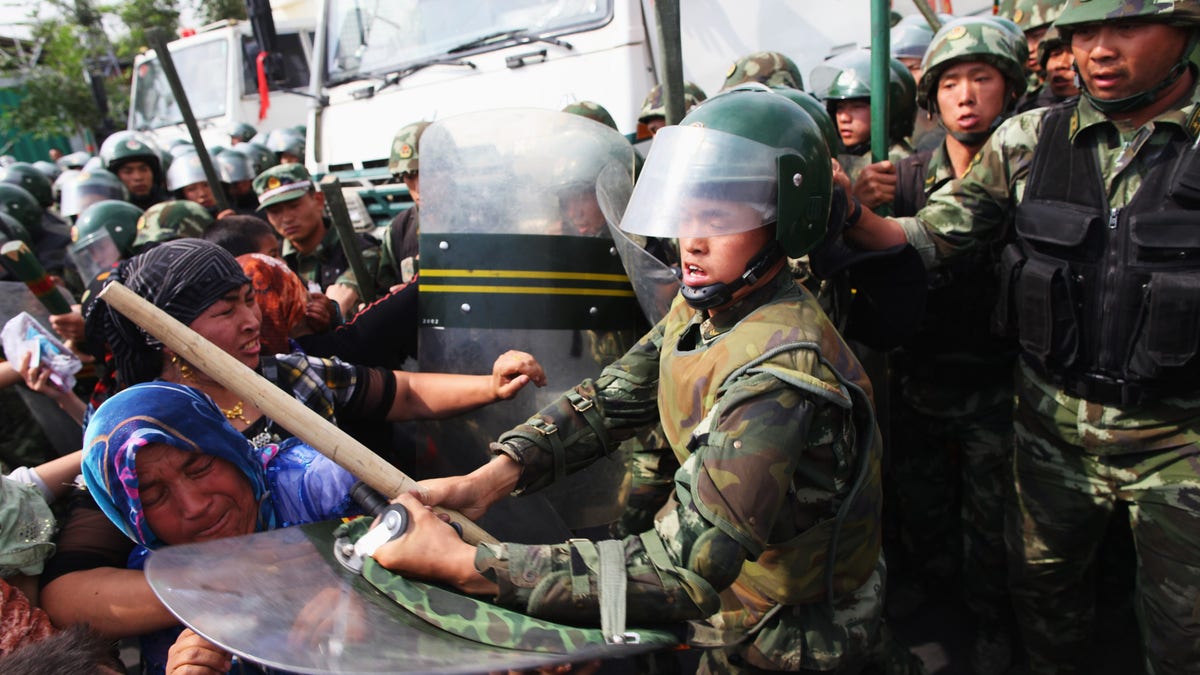 Chinese policemen pushing Uighur women protesting on a street in Urumqi