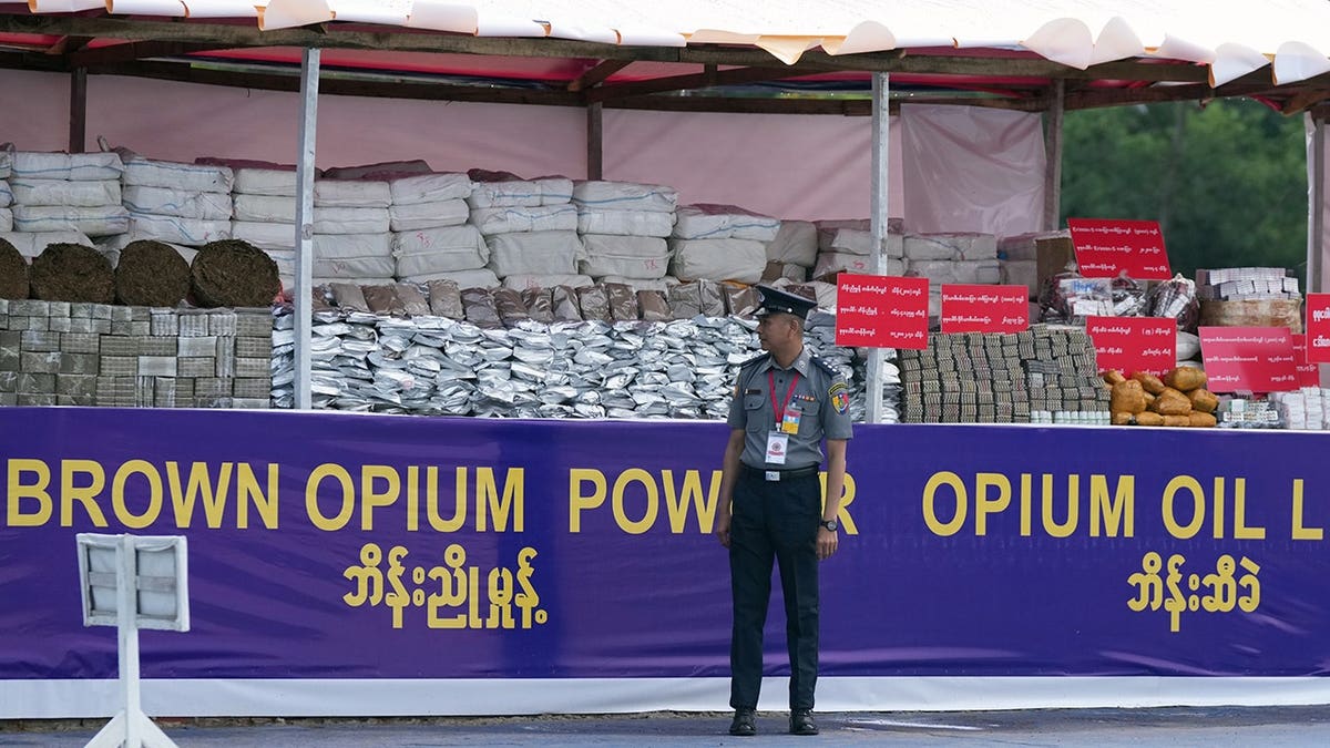 Police officer stands next to confiscated drugs in Burma