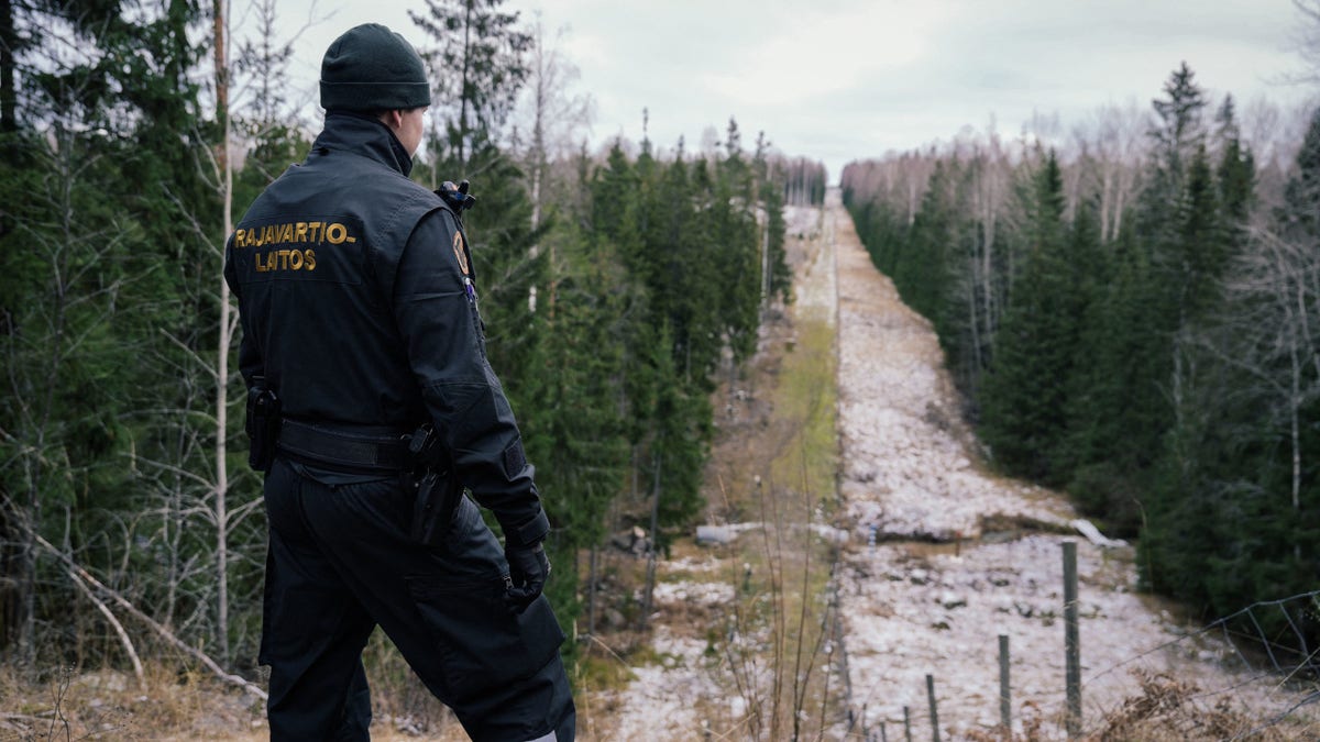Senior border guard officer Juho Pellinen looking at fence marking Finland Russia border near Pelkola crossing