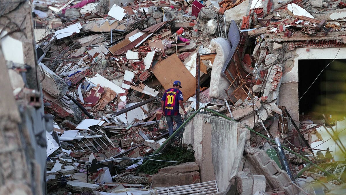 man stands on earthquake rubble in Venezuela
