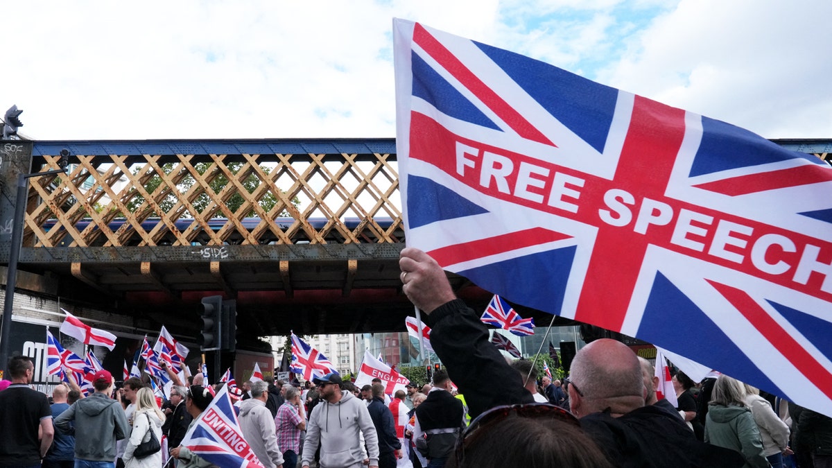 Supporters of British activist Tommy Robinson walk through central London waving flags during a 'Free speech' march, on September 13, 2025.