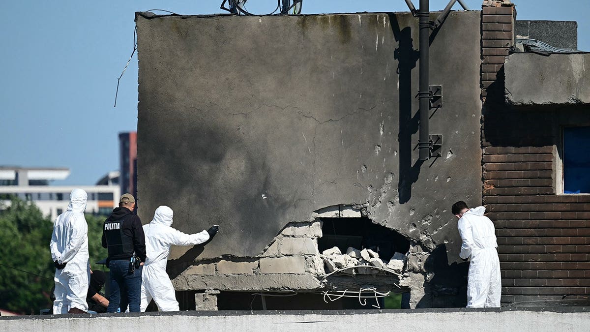 Police and forensic investigators examine damage at an apartment building struck by a Russian drone.