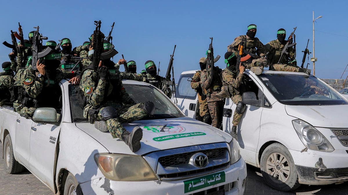 Hamas fighters stand in formation on Gaza City beachfront during hostage handover.