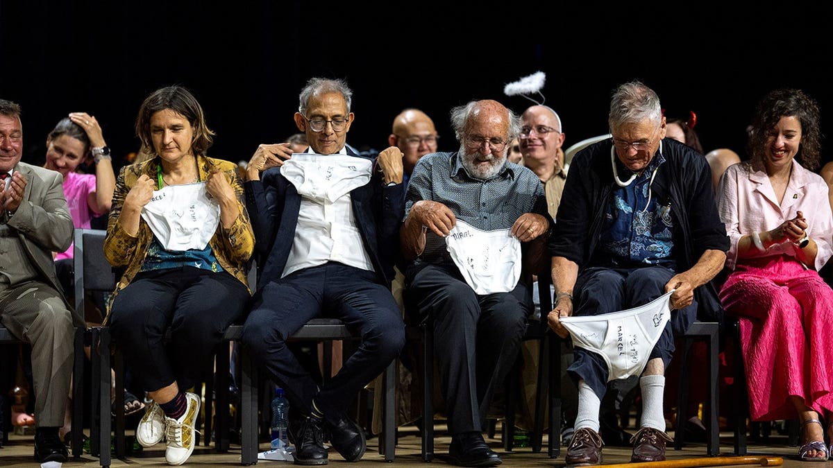 Esther Duflo, Abhijit Banerjee, Michel Mayor and Tim Hunt examine underwear at an awards ceremony.