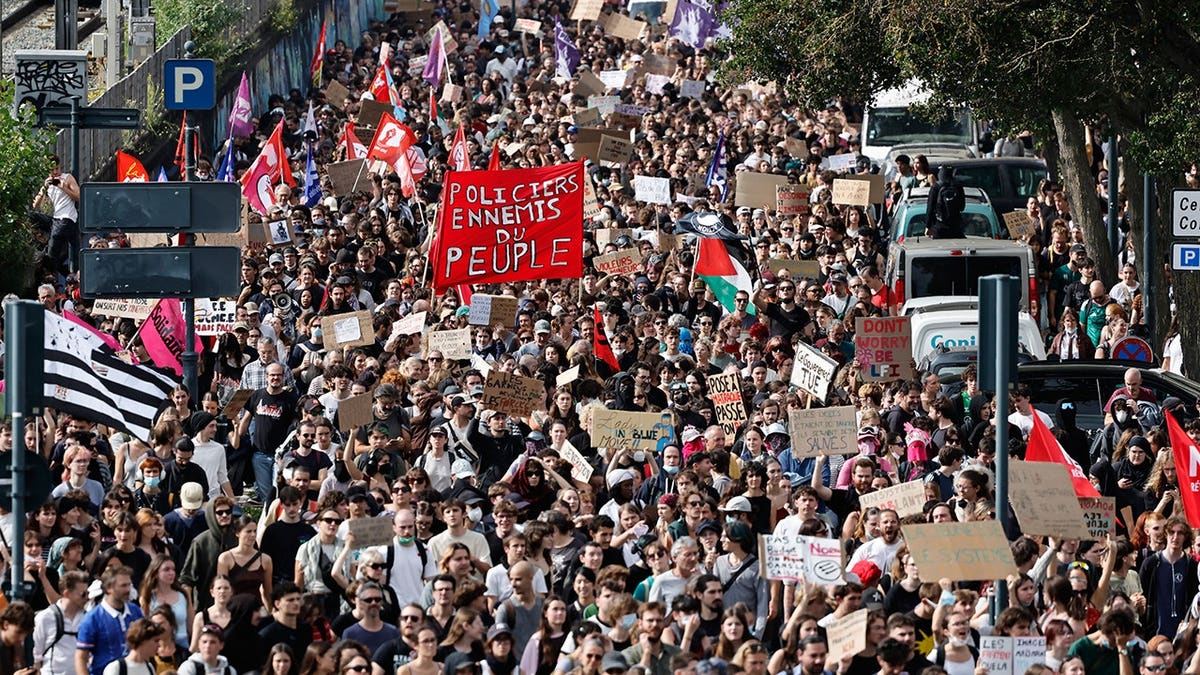 Students march with a large red banner reading 'Police officers, enemy of the people' during a protest in Rennes, France.