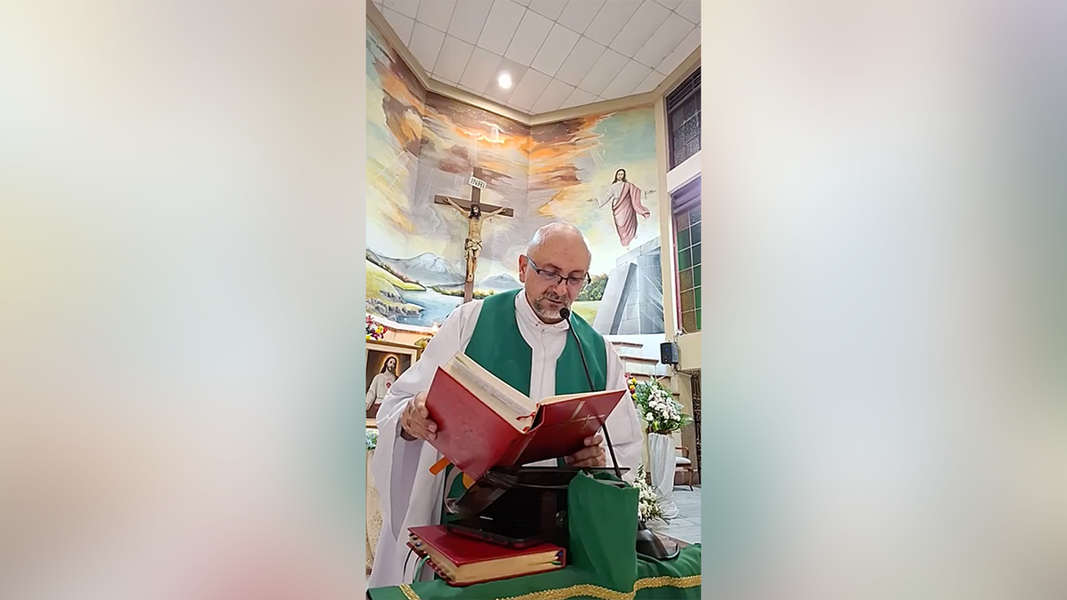 Father Patricio Alfredo Sánchez Molinari reads from a book during Mass with a crucifix behind him