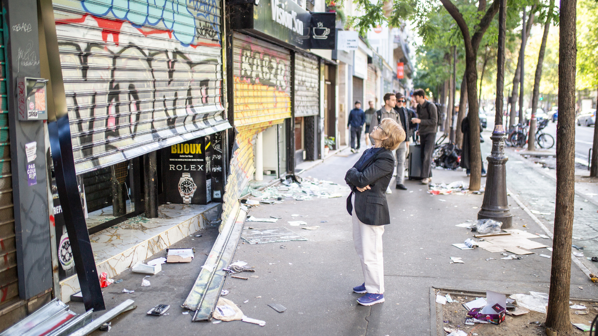People walk by looted shops after a day of violent clashes between police and protesters amid a nationwide mobilisation over rising living costs, fuel prices and education funding in Paris, France, on October 18, 2026.