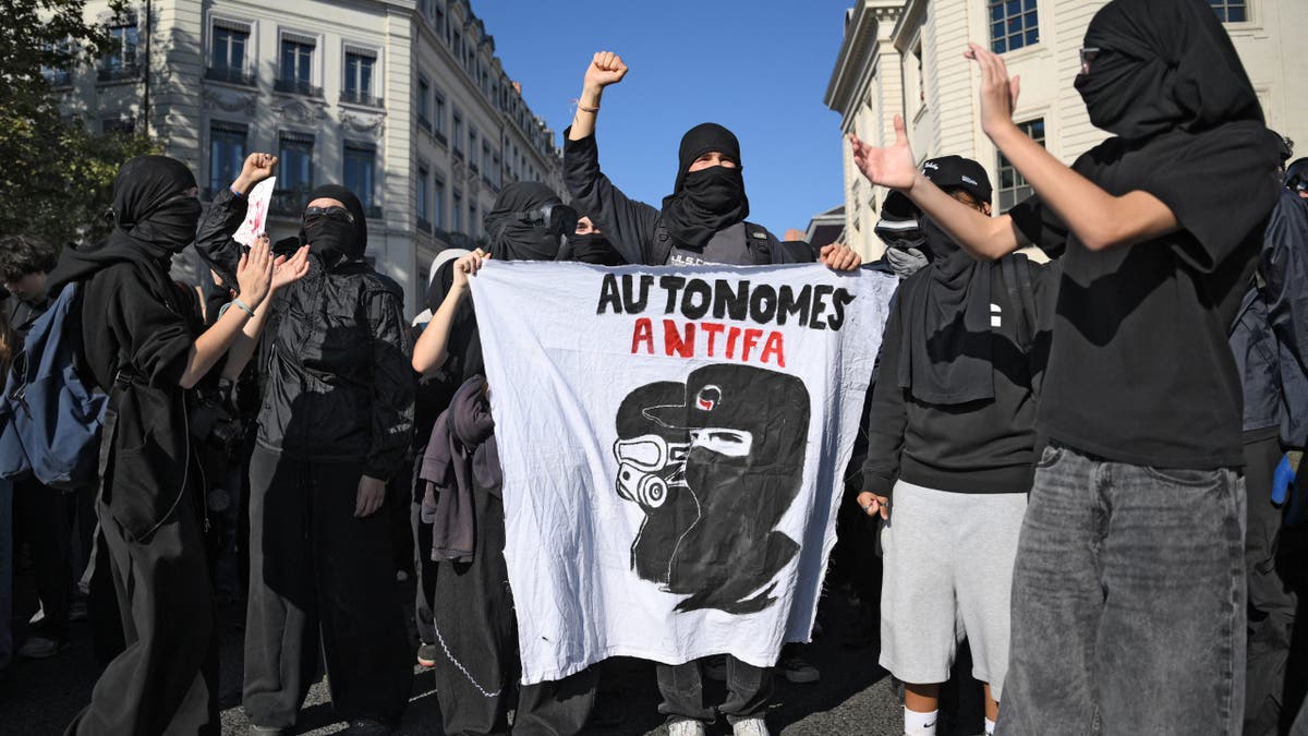 Masked protesters hold a banner reading