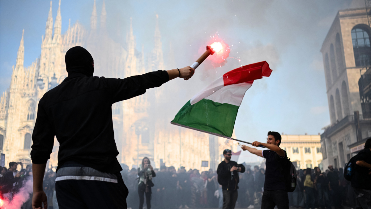 Demonstrators light flares during an anti-government protest organized by the Italia in Piazza movement, at Piazza Duomo in Milan, on October 17, 2026.