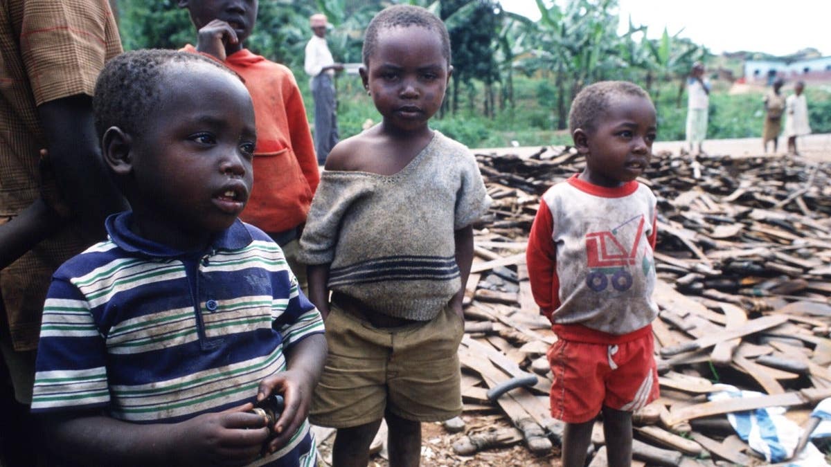 Children stand next to a pile of machetes that were used to kill Tutsis in Rwanda.