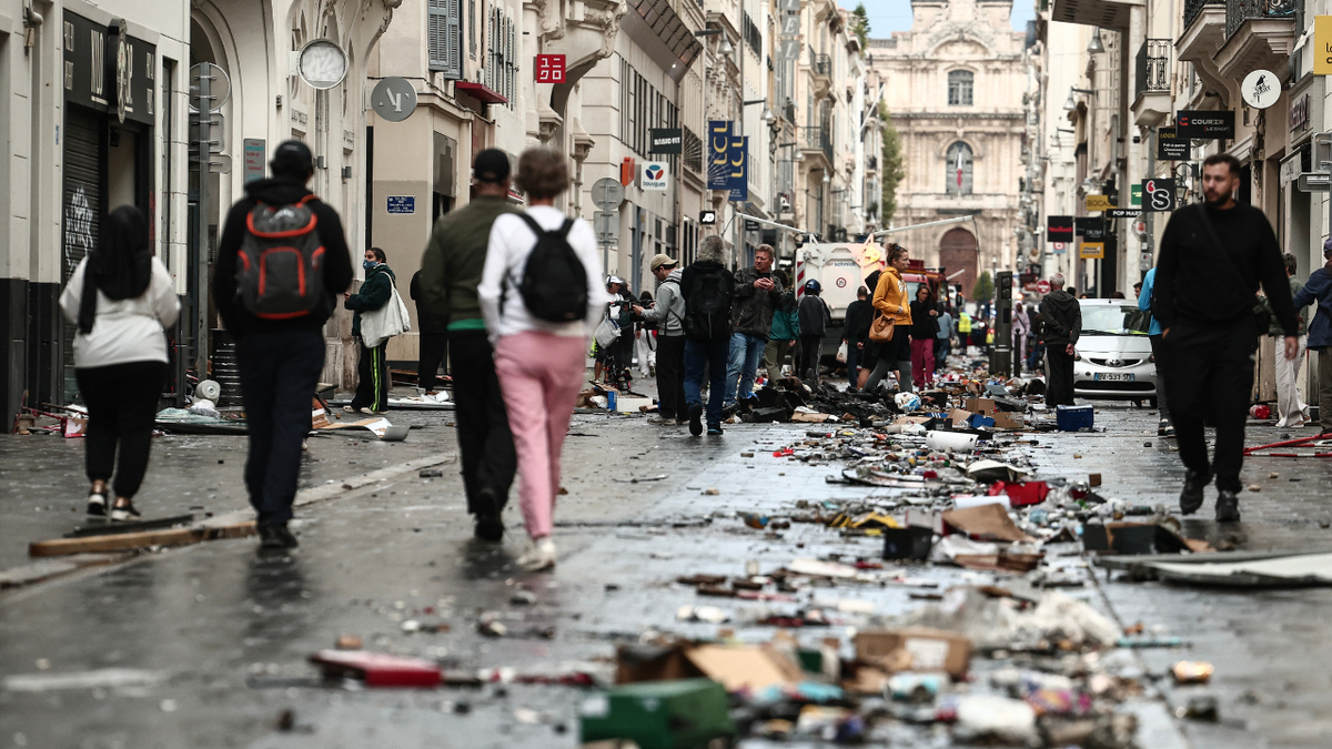 Pedestrians walk along a street covered in debris a day after nationwide protests against the "high cost of living", in Marseille on October 18, 2026.