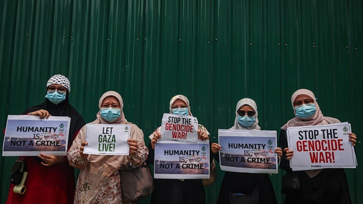 Women hold placards reading